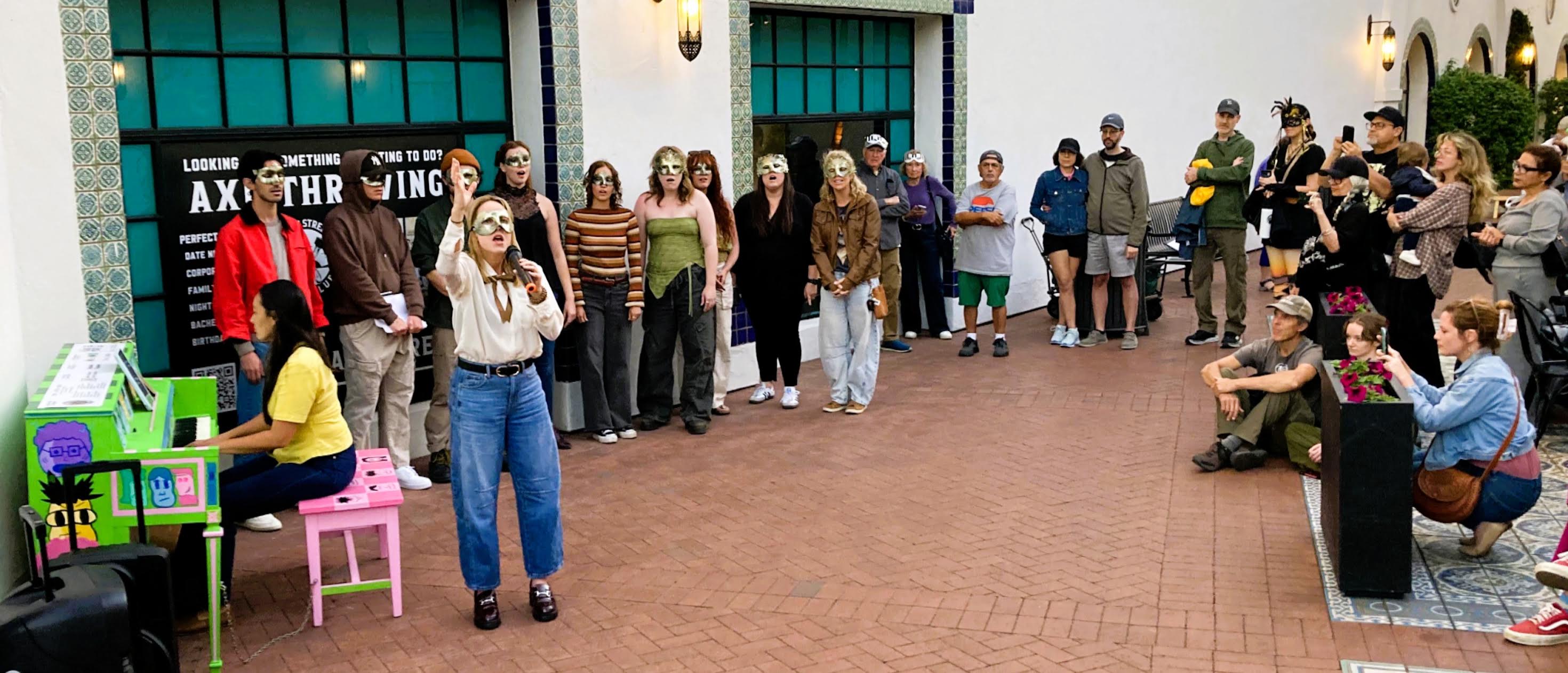 A crowd of masked performers at the Masq(p)arade 2026 Santa Barbara event on State Street